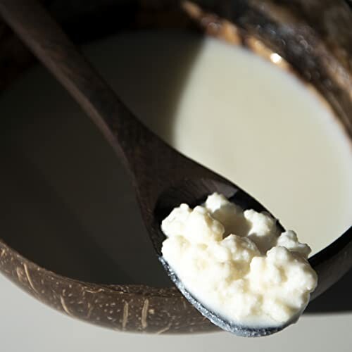 Close-up of a wooden spoon with yogurt in a bowl.